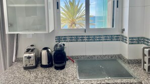 Una cocina con ventana, tostadora, hervidor y cafetera.