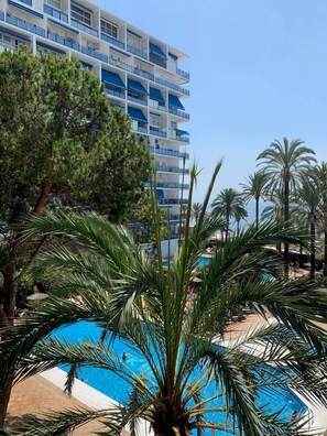 Ein Hotel mit Pool, umgeben von Palmen und blauem Himmel.