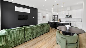 A modern kitchen with white cabinets, a black countertop, and a green sofa.