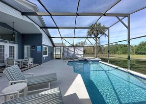 Ein Poolbereich mit Liegestühlen, einer überdachten Terrasse und Blick auf die umliegende Landschaft.