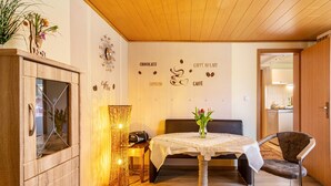Un espace repas comprenant une table, des chaises, un mur décoratif orné de mots liés au café, un meuble en bois et un lampadaire.