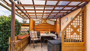 Un patio couvert avec des meubles en bois, une table et un ventilateur décoratif.