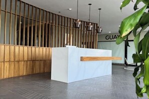 A reception desk with a wooden slat partition, a white reception area, and pendant lighting. - Artemisa : Modern apt. 1Hab. • Comfort and secure location (Tegucigalpa)