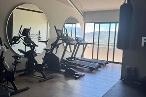 A gym with exercise equipment, large mirrors, and a view of the mountains. - Artemisa : Modern apt. 1Hab. • Comfort and secure location (Tegucigalpa)