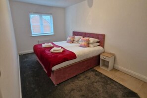 Une chambre à coucher avec un lit, une table de chevet, une fenêtre et un radiateur.