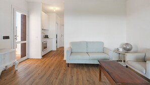 Un salon avec un canapé, une table basse et une petite table sur laquelle se trouve un ventilateur.
