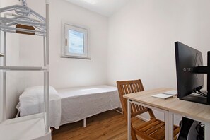 A small, single-room accommodation with a bunk bed, a desk with a computer, and a window. - Holiday Home 'Calipso' with Sea View, Wi-Fi and Air Conditioning (Stintino)