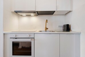 A compact kitchen with a built-in oven, a single sink with a gold faucet, and a compact range hood. - Holiday Home 'Calipso' with Sea View, Wi-Fi and Air Conditioning (Stintino)