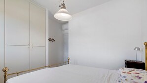 Une chambre à coucher comprenant un lit, une armoire, une table de chevet et une lampe suspendue.