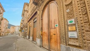 Calle con una puerta de madera grande, un letrero que dice 'L'Opera' y un letrero 'RCS' en un edificio.
