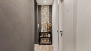 A hallway with a patterned wallpaper, a black console table with decorative items, and a wooden floor. - Rooms La Spezia (La Spezia)