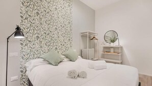 A neatly made bed with pillows, a bedside lamp, a mirror, and a shelf with toiletries. - Rooms La Spezia (La Spezia)