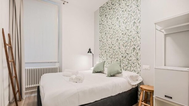 Un dormitorio con cama, un radiador, un escritorio y un espejo.