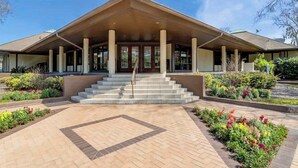 A building with a covered entrance, steps leading up to it, and a landscaped garden area. - Pet-Friendly Shipyard Retreat | Pool & Tennis (Hilton Head Island)