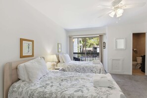 A hotel room with two beds, a ceiling fan, a view of the outside, and a bathroom. - Pet-Friendly Shipyard Retreat | Pool & Tennis (Hilton Head Island)