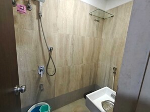 A bathroom with a shower, a toilet, and a glass shelf. - Hotel Zampex Executive (Mumbai)