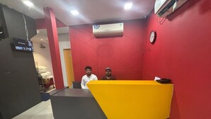 Un comptoir d’accueil aux couleurs jaune et gris, un mur rouge et un appareil de climatisation installé au-dessus.