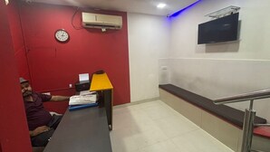 Un espace d’accueil comprenant un comptoir, une horloge, un appareil de climatisation, un téléviseur et un escalier.