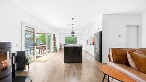 Una cucina moderna con isola centrale, un'area pranzo con tavolo e sedie, e un soggiorno con divano.