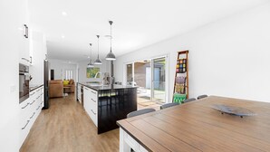 Una cucina moderna con isola centrale, un'area pranzo con tavolo in legno e un soggiorno con divano e tavolino.
