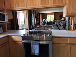 A kitchen with wooden cabinets, a microwave, a stove, and a dining area with a table and chairs.