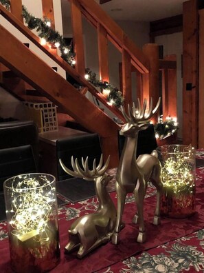 A dining area with a wooden staircase, a table set with candles, and a deer figurine.