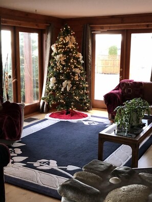 Un salon avec un sapin de Noël, un canapé, une table basse et une grande fenêtre.