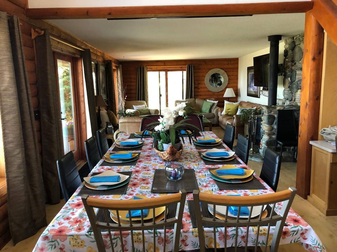 Un espace repas avec une longue table dressée pour un repas, entourée de chaises.