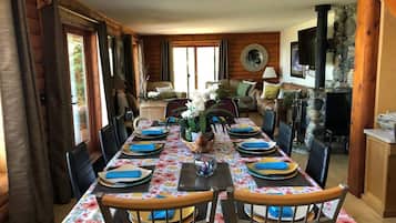 Un espace repas avec une longue table dressée pour un repas, entourée de chaises.
