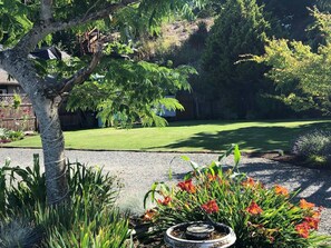 Un jardí paisatjistic amb un arbre, plantes florals i un pràt.