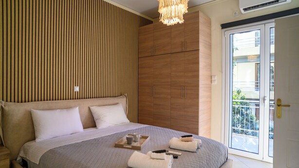 Ein Schlafzimmer mit einem großen Bett, einem Holzschrank und einer Schiebetür zum Außenbereich.