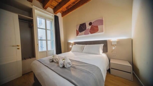 Un dormitorio con cama, mesitas de noche, un armario y una obra de arte abstracto colgada en la pared.