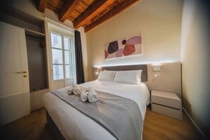 A bedroom with a bed, bedside tables, a wardrobe, and a wall-mounted abstract art piece. - Verona in Love: 2 steps from the Arena | Modern Elegance with Private Balcony (Verona)