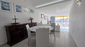 Un comedor con una mesa redonda, sillas, un armario de madera y cuadros en la pared.