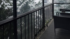 A covered balcony with a view of snow-covered trees and buildings.