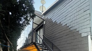 A modern building with a staircase leading to an upper level, surrounded by trees.