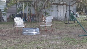 Un jardin avec deux chaises blanches, une table en métal et une balançoire.