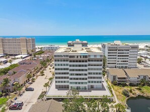 Ein modernes Hotel mit mehreren Etagen, einem Parkplatz und Blick auf Strand und Meer.