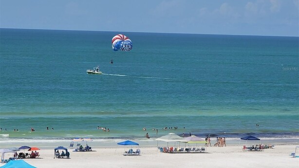 Ein Strand mit Fallschirm, Jetski und badenden Personen.