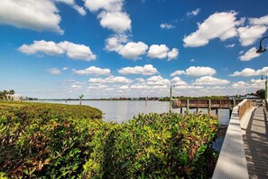 A waterfront park with a wooden boardwalk, a wooden bridge, and a clear blue sky with clouds. - Beautifully appointed, bright and airy unit with all the right touches! (Siesta Key)