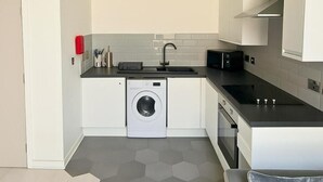 A compact kitchen with a washing machine, a microwave, and a sink.