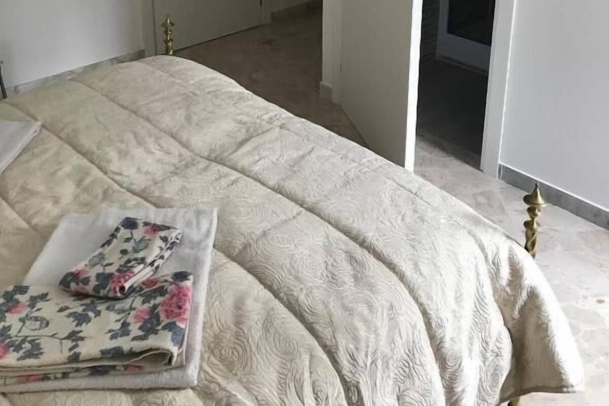 Un dormitorio con cama, puerta y armario abierto.