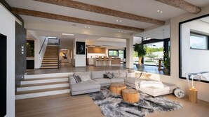 A spacious living area with a large sectional sofa, a wooden staircase, and a view of the outdoors. - Luxury Villa West Nice (Nice)