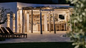 A modern building with a covered outdoor area, a pool, and lounge chairs. - Luxury Villa West Nice (Nice)