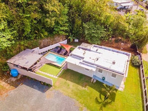 Ein Wohnhaus mit Swimmingpool, überdachter Terrasse und großem Garten.