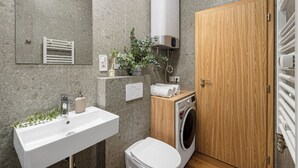 Un bagno moderno con lavandino, specchio, porta asciugamani, termosifone e porta in legno.