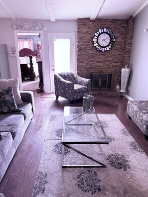 Ein Wohnzimmer mit einer Couch, einem Sessel, einem Couchtisch und einem gemusterten Teppich.
