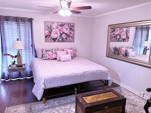 Ein Schlafzimmer mit einem Bett, einem Nachttisch, einer Lampe, einem Spiegel und einer Zierkommode.
