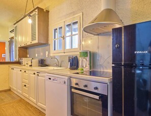 A kitchen with a dishwasher, oven, coffee maker, and a black refrigerator. - Astrakeri Gardens Villa (Corfu)
