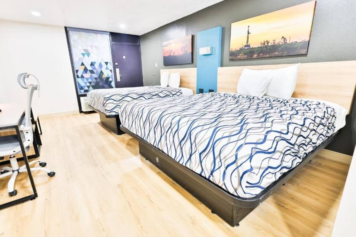 A hotel room with two beds, a desk, and exercise equipment.